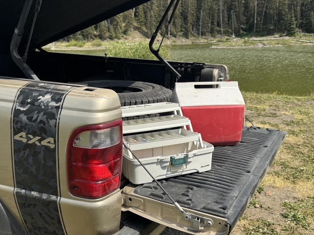 Open tailgate at the lake with tackle box and cooler on the bed